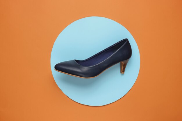Foto zapatos clásicos de mujer de tacón en papel marrón con círculo azul pastel en el medio