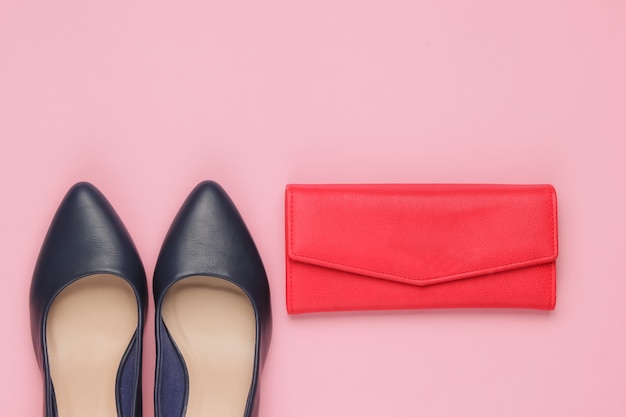 Zapatos clásicos de tacón, billetera de cuero rojo sobre rosa.