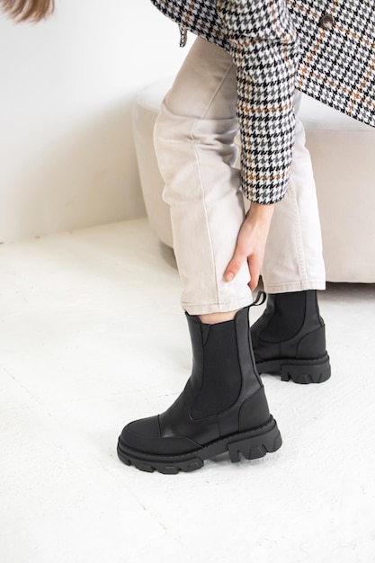 Zapatos cómodos y elegantes de mujer, botas de invierno con materiales naturales, piel. Estilo casual para todos los días. Chica de moda en chaqueta y pantalón blanco