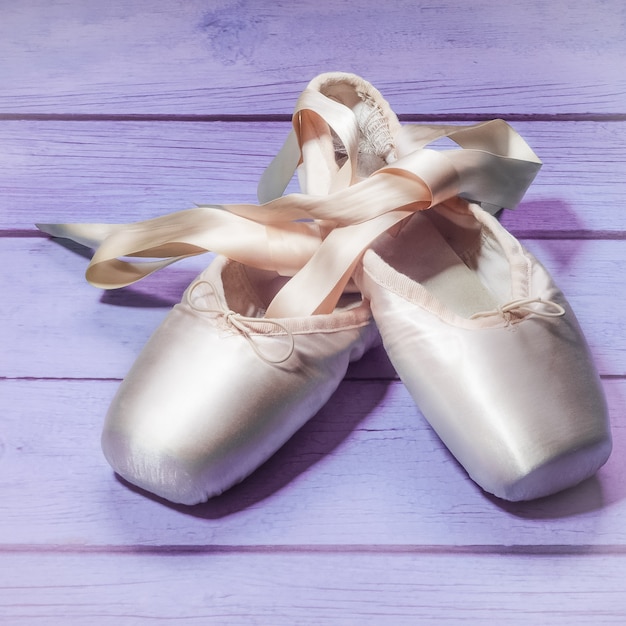 Foto zapatos de la danza del ballet de los zapatos de pointe con un arco de cintas en un fondo de madera.