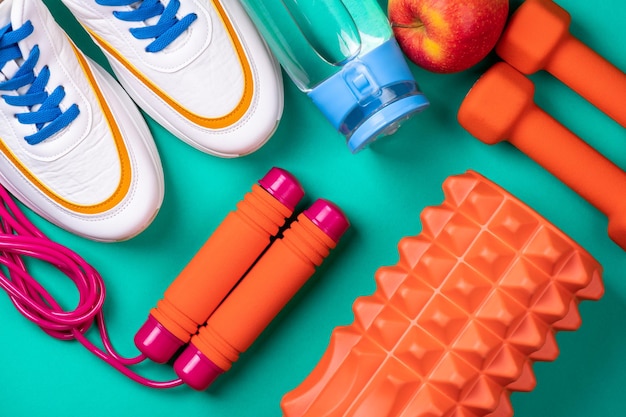 Foto zapatos y equipos deportivos para el fitness estilo de vida saludable ejercicio concepto de comida saludable fondo deportivo con equipos deportivos zapatos pesas para saltar cuerda fruta y botella de agua sobre fondo azul