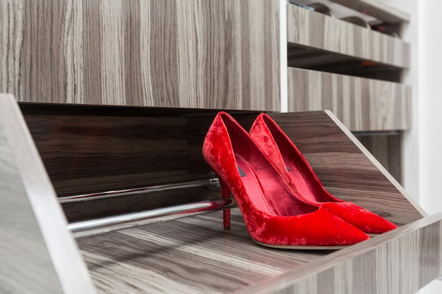 Zapatos femeninos de gamuza roja en un estante en un armario