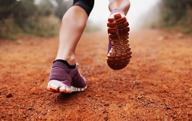 Foto zapatos de fitness y mujer corriendo en el parque de primer plano para entrenamiento de ejercicio o bienestar al aire libre zapatillas de entrenamiento y piernas de corredora femenina en la naturaleza para deportes de cardio matutinos o rutina de carrera de maratón