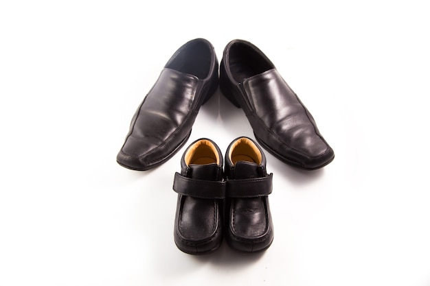 Zapatos grandes y pequeños de piel negra sobre fondo blanco. Composición del día del padre
