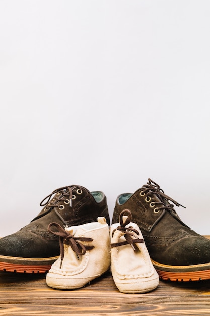 Foto zapatos masculinos cerca de botas de niño en tablero de madera