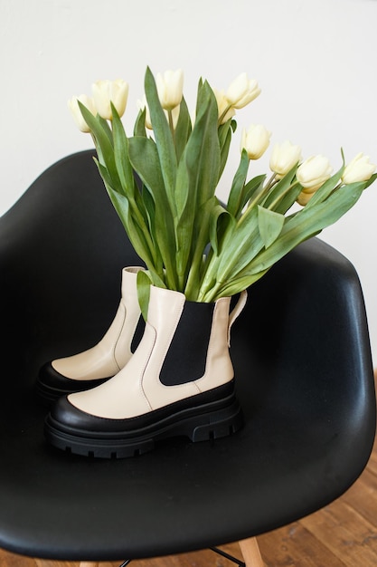 Zapatos de moda que se paran en una silla Hay tulipanes en los zapatos Día Internacional de la Mujer