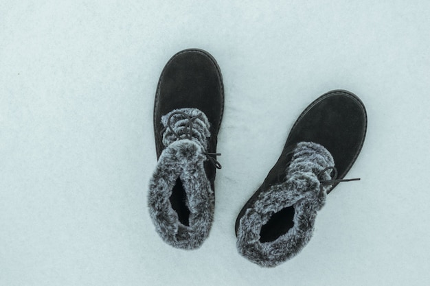 Zapatos de mujer cálidos de moda sobre un fondo nevado. Preciosos y prácticos zapatos de invierno para mujer.