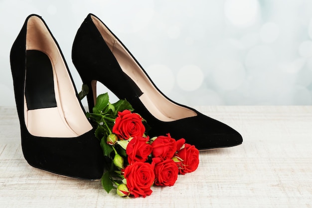 Zapatos de mujer hermosa con flores sobre fondo brillante