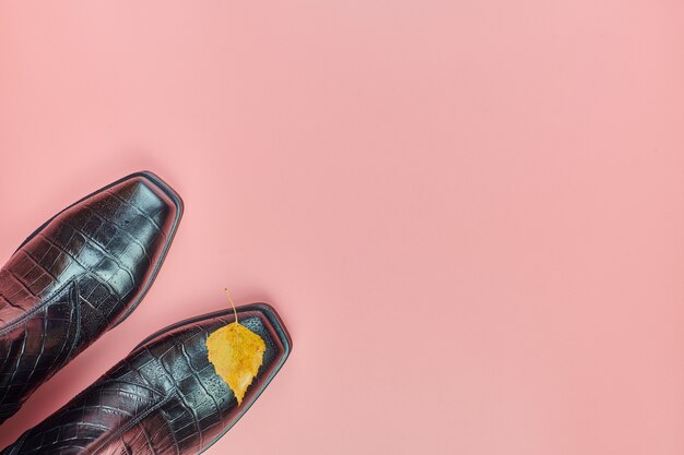 Zapatos de mujer impermeable de otoño con gotas de lluvia, espacio de copia. Concepto de cuidado del calzado. Botas impermeables con hoja de otoño como símbolo del tiempo lluvioso.