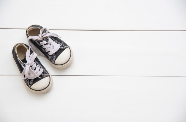 Zapatos negros para niños sobre suelo de madera.