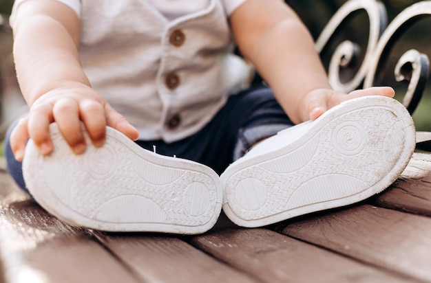 Zapatos de niños. Zapatos de bebé sentado en un banco del parque