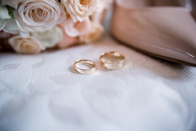 Zapatos de novia con anillos de boda y ramo de oro.