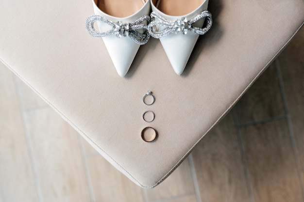 Los zapatos de novia de boda con anillos dorados están en la silla