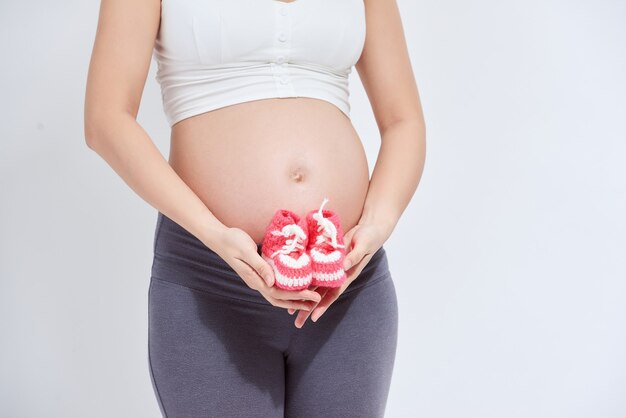 Zapatos pequeños para el feto en el vientre de la mujer embarazada