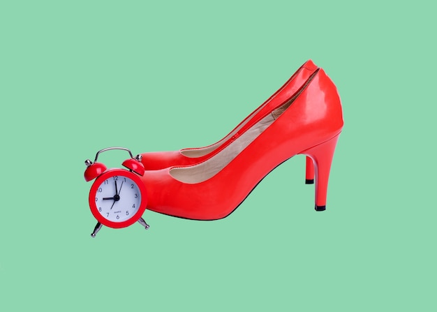 Zapatos rojos y alarma sobre fondo verde