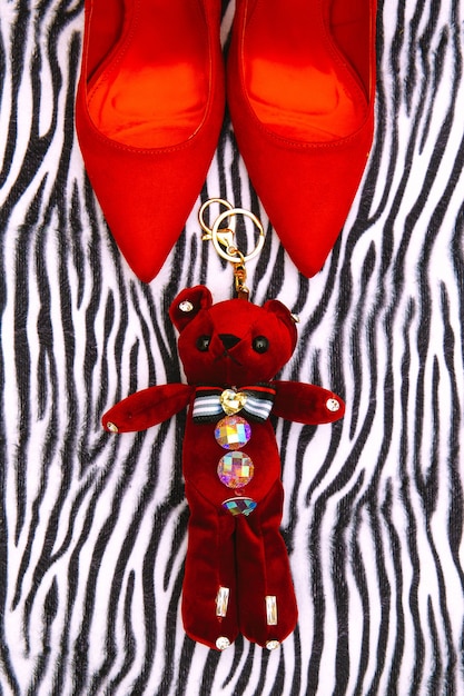 Zapatos rojos y oso de juguete sobre fondo de estampado de cebra Concepto de moda de regalo