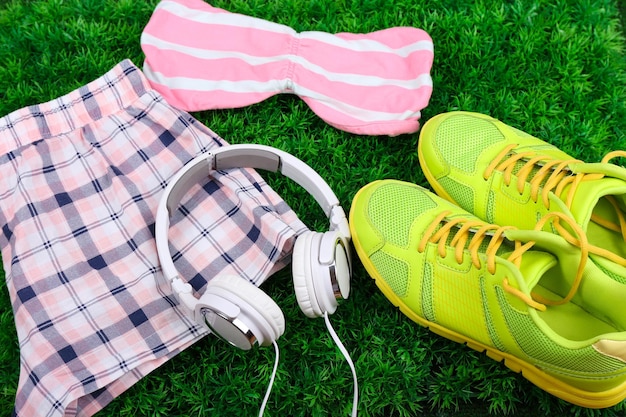 Zapatos de ropa deportiva y auriculares sobre fondo de hierba verde