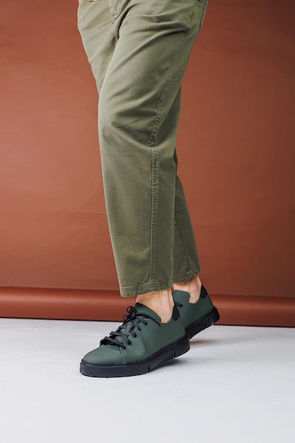 Zapatos de verano Primer plano de piernas masculinas en pantalones verdes y zapatillas de deporte casuales verdes Zapatos de cuero de verano para hombres