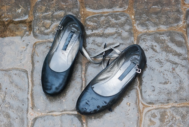 Zapatos viejos están en la calle bajo la lluvia, zapatos mojados.