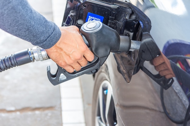 Foto zapfpistole addieren brennstoff im auto an der tankstelle