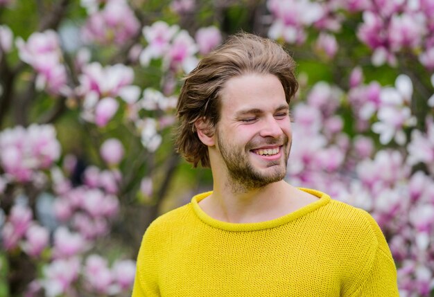 Zarte Blumen. Hipster genießen Blüte. Frühlingskonzept. Kerl entspannen sich im Blumenpark. Botanischer Garten. Botanik und Natur. Mann blüht Hintergrund unscharf. Frühlingsschönheit. Frische und Erwachen.