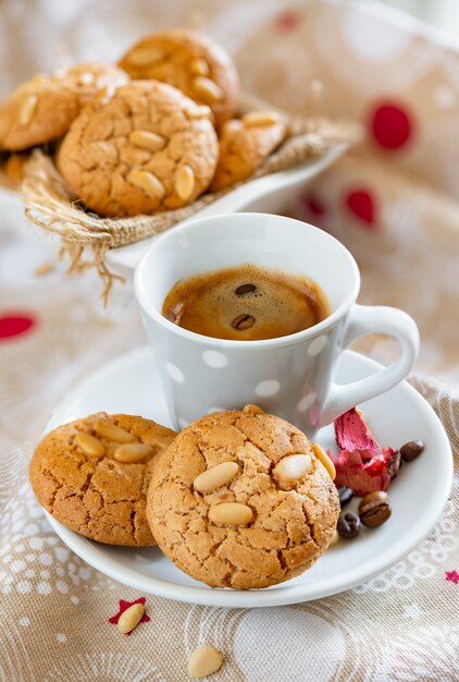 Zarte Butterkekse mit knusprigen frischen Pinienkernen und Kaffeetasse