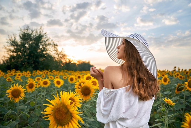 Zarte Frau, die unter Feld mit Sonnenblumen aufwirft