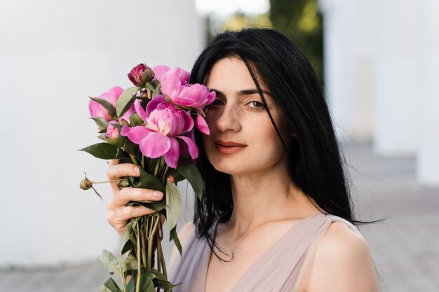 Zarte georgische Frau mit Blumenstrauß Pfingstrosen Attraktives Modell in modischem Kleid mit Blumen Lifestyle