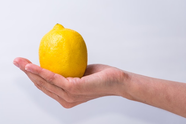 Zarte Hand mit einem zitronengelben Obst und Gemüse gesunder Lebensstil