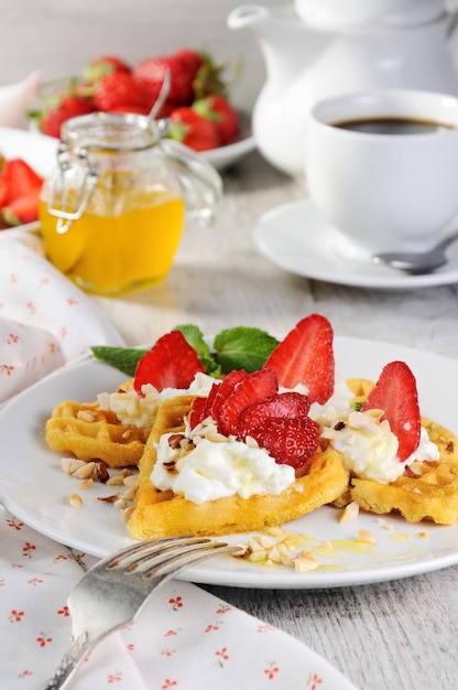 Zarte, köstliche belgische Waffeln mit Erdnüssen und Honig mit Sahne-Erdbeergeschmack