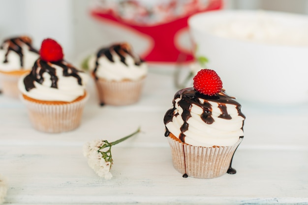 Zarte leckere Muffins, dekoriert mit Himbeeren und gegossenem Witz