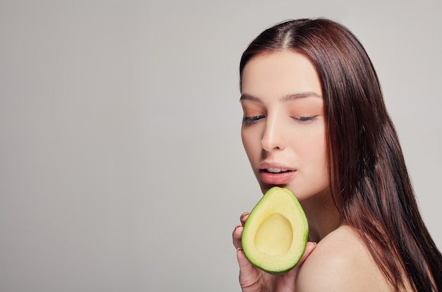 Zarte und ruhige Dame mit der Avocado in der Hand, die unten schaut