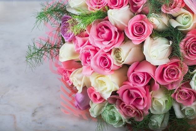 Zarter Hochzeitsbrautstrauß der schönen weißen und rosa Rosen auf einem weißen Marmortisch
