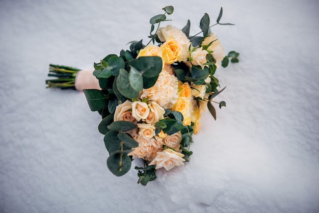 Foto zarter hochzeitsstrauß aus frischen blumen auf flauschigem schnee, nahaufnahme beige rosen auf weißem, gefrorenem hintergrund winterhochzeit kopieren sie platz