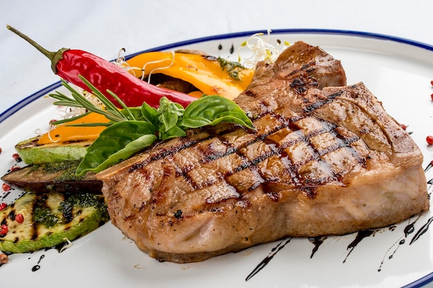 Zartes gegrilltes Steak oder Tbone-Steak, serviert mit gegrilltem Gemüse auf einem weißen Teller