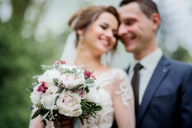 Zartes Hochzeitspaar wirft in einem grünen Park auf