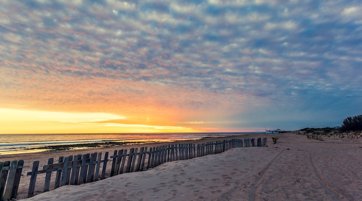 Foto zaun am sandstrand bei sonnenuntergang in chipiona