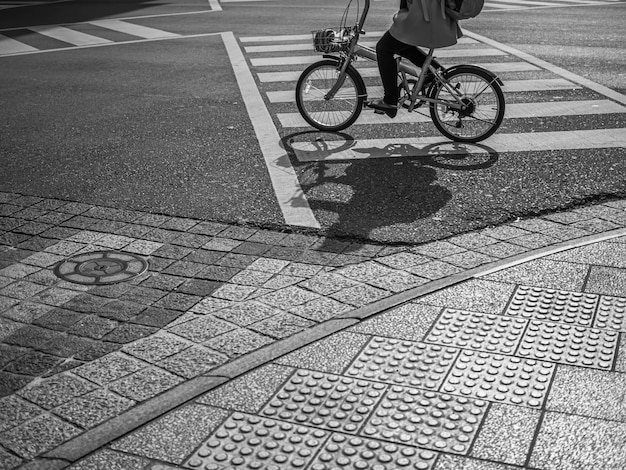 Zebrastreifen, Asphaltstraßenbeschaffenheit und Frau, die das Fahrrad in der Stadt reiten