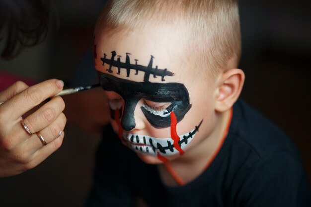 Zeichne auf das Gesicht des Jungen. Emotionales Porträt mit einem furchtsamen Zombie auf seinem Gesicht