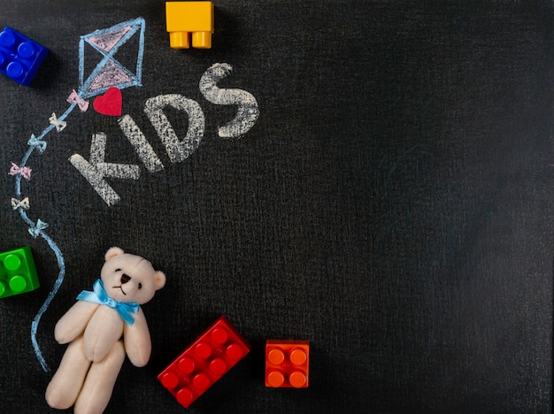 Zeichnen auf Sandpapier. Die Kinder, die auf Tafel und Teddybären mit geschrieben werden, bauen Stücke zusammen. Hintergrund Textfreiraum.