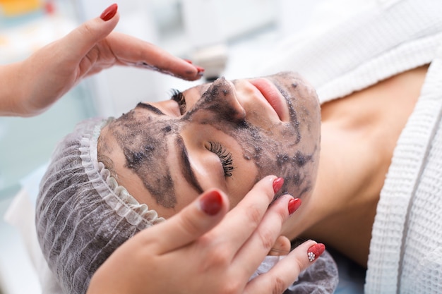 Foto zeichnen einer schwarzen maske auf das gesicht des patienten. schönheitssalon.