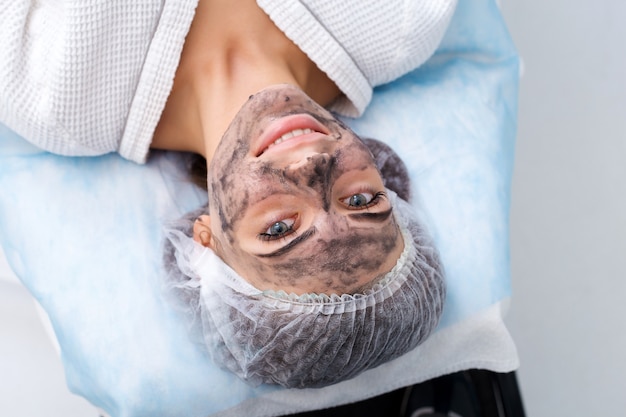 Foto zeichnen einer schwarzen maske auf das gesicht des patienten. schönheitssalon.