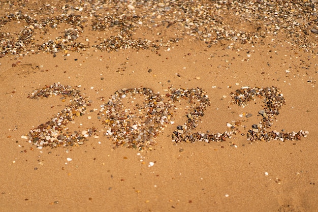 Zeichnet auf sand an einem strand mit einer welle am meer urlaub am meer neujahrskonzept