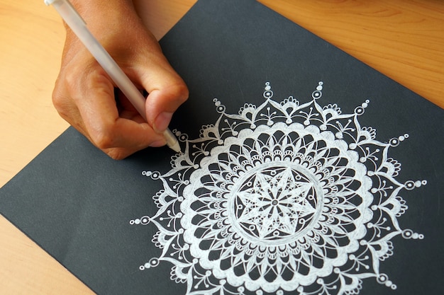 Zeichnung eines Mandala-Entwurfs auf einem schwarzen Hintergrund