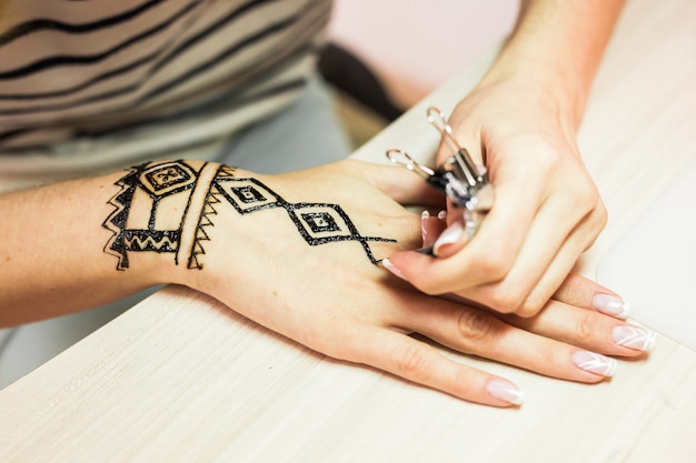 Zeichnungsprozess von Henna-Menhdi-Ornament auf der Hand der Frau.