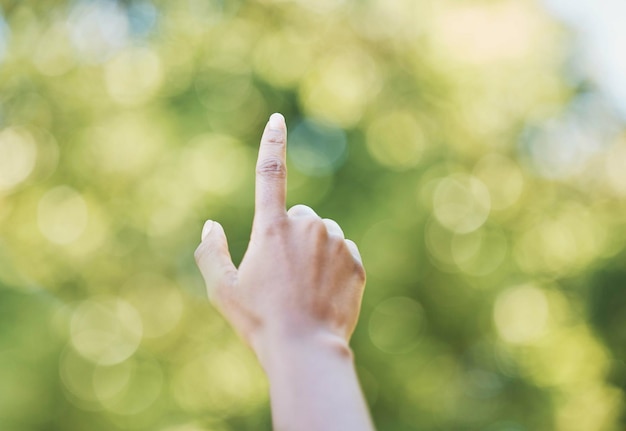 Zeigefinger der Hand und zeigt in der Natur im Freien oder im Park auf etwas Richtung Bokeh und Hände zeigen nach oben für Gestensignal oder Gebärdensprache, die Finger zählt oder Emoji-Mathematik oder Timer