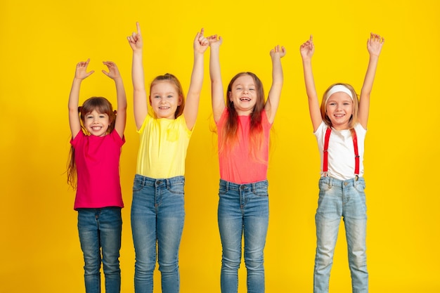 Zeigen. Glückliche Kinder, die zusammen an der gelben Studiowand spielen und Spaß haben.