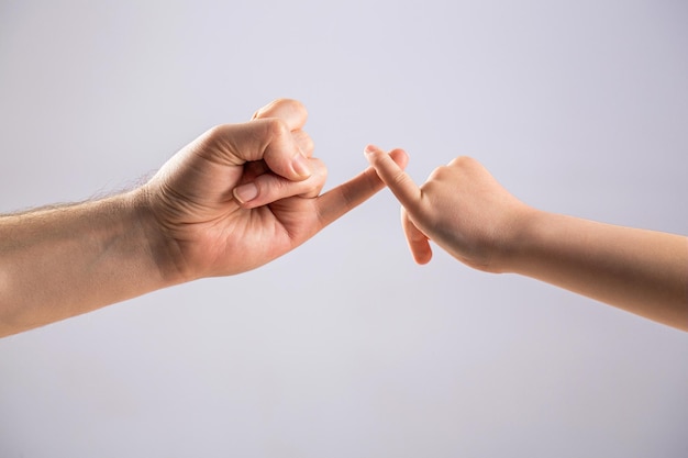 Zeigen Sie Freundschaft und Vergebung. Vater-Tochter-Hand macht Versprechen, Freundschaftskonzept. Kind haken kleinen Finger zusammen. Kleiner Finger der beiden Hände hält zusammen