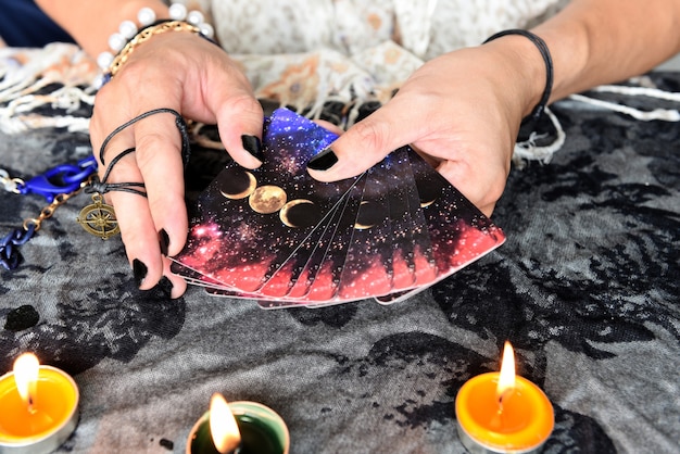 Foto zeigen sie wahrsager von händen, die tarot-karten und tarot-leser mit kerzenlicht auf dem tisch halten, durchführen von magischen darbietungen, mystische astrologen, die das konzept vorhersagen