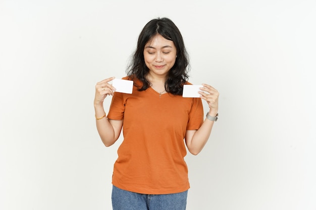 Zeigt leere Kreditkarte einer asiatischen Frau mit orangefarbenem T-Shirt isoliert auf weißem Hintergrund